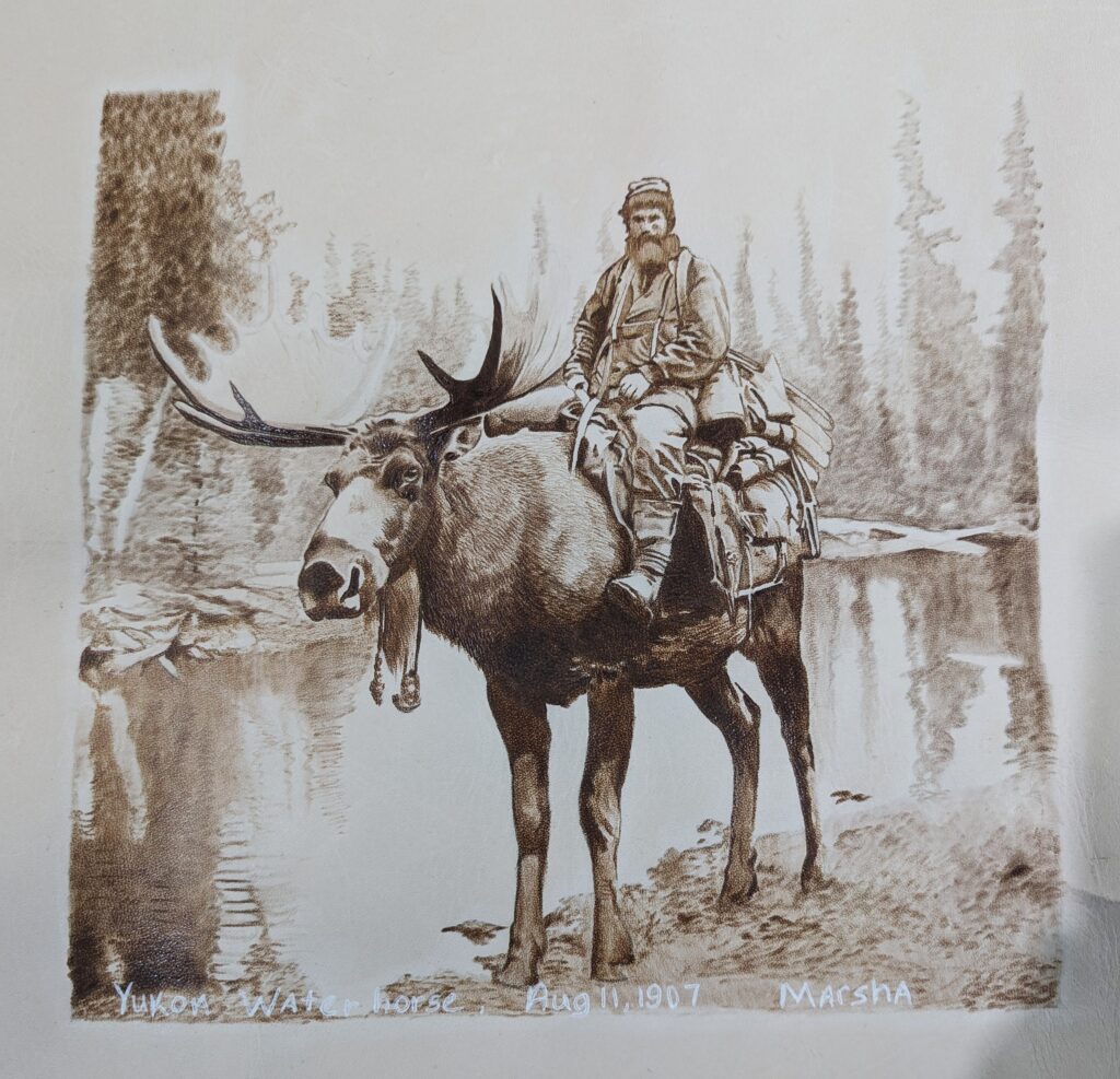 Marsha Wilson-Johnson, "Yukon Water Horse", 2023; Vegetable tanned cowhide leather, pyrography with a hand-held wood burner, white ink, shoe polish, blue knotty pine frame; Courtesy of High Desert Fine Art Gallery.